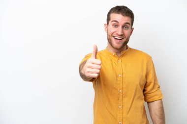 Beyaz arka planda izole edilmiş beyaz bir genç. Başparmakları havada. Çünkü iyi bir şey oldu.