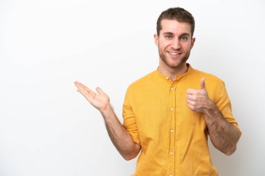 Beyaz arka planda izole edilmiş genç beyaz bir adam, bir ilan vermek ve onaylamak için avucunda hayali bir kopyalama alanı tutuyor.