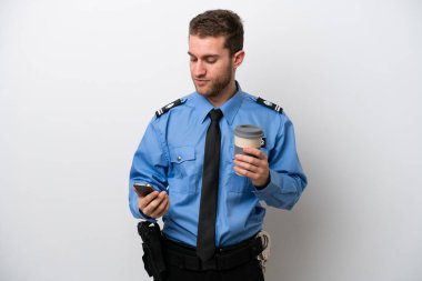 Beyaz arka planda izole edilmiş genç bir beyaz adam elinde kahve ve bir cep telefonu tutuyor.