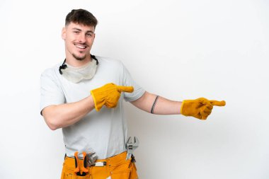 Beyaz arka planda izole edilmiş beyaz tenli elektrikçi parmağını yana uzattı ve bir ürün sundu.