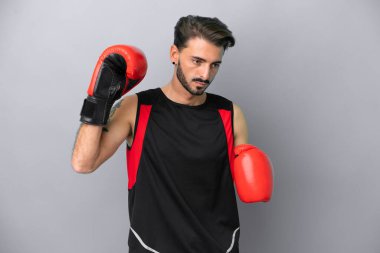 Gri arka planda boks eldivenli, beyaz, genç bir adam.