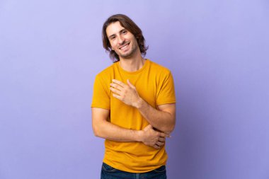 Mor arka planda yalnız, yakışıklı bir adam gülüyor.