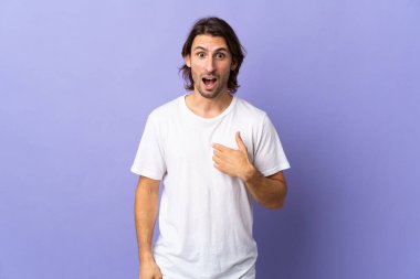 Mor arka planda yalıtılmış, yüzünde sürpriz ifade olan yakışıklı bir adam.