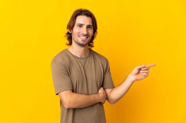 Sarı arka planda izole edilmiş genç ve yakışıklı bir adam.