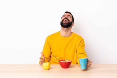 Kafkasyalı bir adam kahvaltısını masada gülüyor..