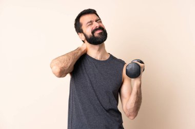 Sakallı, beyaz tenli, halterci, izole arka planda ağırlık kaldırıyor ve boyun ağrısı çekiyor.
