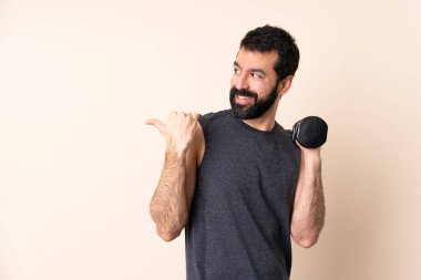 Beyaz sakallı sporcu, halter kaldırıyor izole edilmiş arka planda bir ürün sunmak için yan tarafı işaret ediyor.