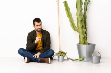 Bahçıvan içeride yerde oturmuş hayal kırıklığına uğramış ve ön tarafı işaret ediyor.