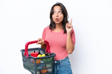 Elinde yiyecek dolu bir alışveriş sepeti tutan genç bir kadın bir fikri işaret ederek...