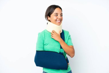 Genç İspanyol kadın boyunluk takıyor ve askısı beyaz arka planda soyutlanmış gülümserken yukarı bakıyor.