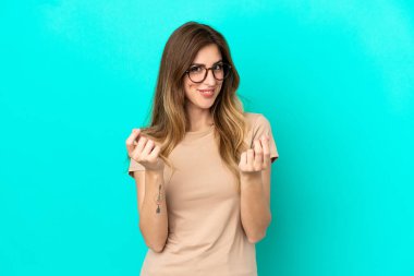 Mavi arka planda izole genç beyaz kadın para hareketi yapıyor.