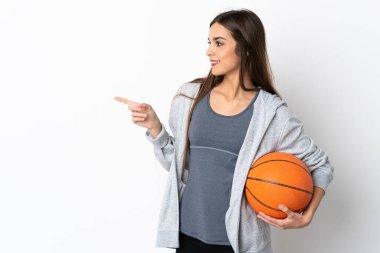 Basketbol oynayan genç bir kadın beyaz arka planda izole edilmiş bir şekilde parmak ucunda bir ürün sunuyor.