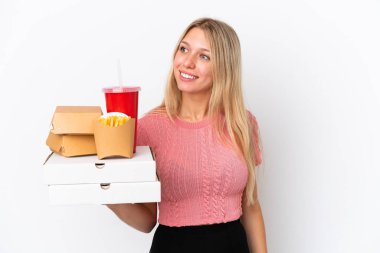 Mavi arka planda yağlı yiyecekler tutan beyaz bir kadın. Yan tarafa bakıyor ve gülümsüyor.