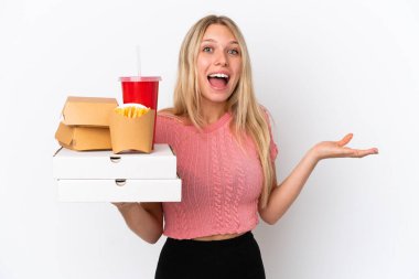 Şişman yiyecekleri mavi arka planda saklayan beyaz kadın şok olmuş yüz ifadesiyle.