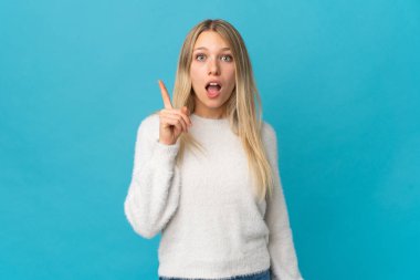 Mavi arka planda izole edilmiş genç sarışın kadın bir fikir düşünüyor.