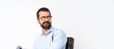 İzole edilmiş beyaz arka planda sakallı genç bir mimar, kafası karışmış bir yüz ifadesi var.