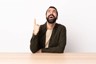 Masada sakallı beyaz bir adam yukarı bakıyor ve şaşırıyor..