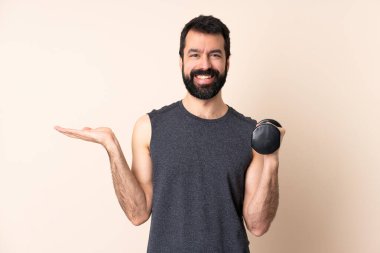 Kafkasyalı sakallı sporcu arka planda ağırlık kaldırıyor. Avucunun içine bir reklam koymak için görsel bir telif alanı tutuyor.