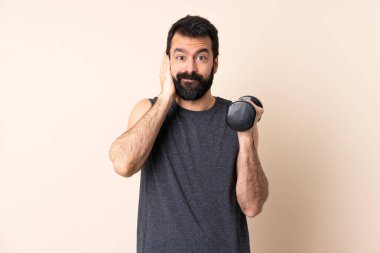 Beyaz sakallı sporcu halter kaldırıyor izole edilmiş arka planda hayal kırıklığına uğramış ve kulaklarını kapatıyor.