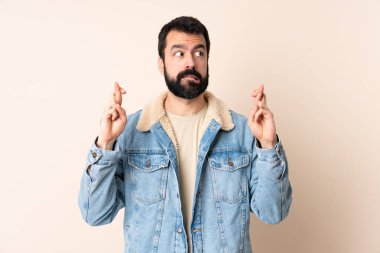 Sakallı beyaz bir adam izole edilmiş, parmaklarını çapraz yapıp en iyisini diliyor.