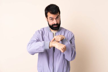 İzole edilmiş arka planda, sakallı, beyaz bir adam geç kalma jesti yapıyor.