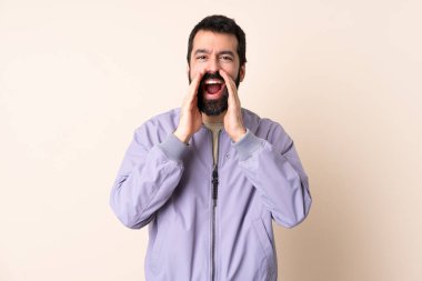 Sakallı, ceketli beyaz bir adam izole edilmiş arka planda bağırıyor ve bir şey duyuruyor.