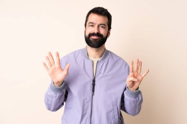 Sakallı, ceketli beyaz bir adam izole edilmiş arka planda dokuzlu parmaklarla sayıyor.