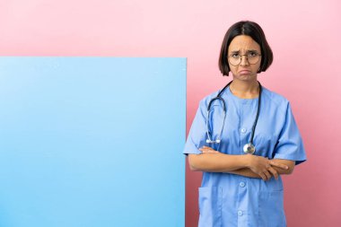 Hüzünlü bir ifadeyle izole edilmiş arka planda büyük bir afişi olan genç melez bir cerrah kadın.