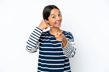 Beyaz arka planda izole edilmiş genç İspanyol bir kadın telefon hareketi yapıyor ve ön tarafı işaret ediyor.