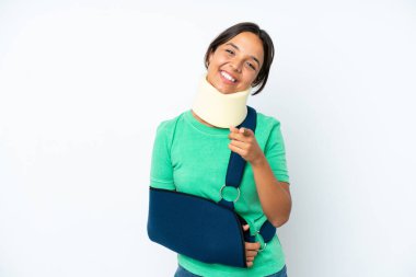 Boynunda boyunluk ve askısı olan genç İspanyol kadın beyaz arka planda izole edilmiş ve mutlu bir ifadeyle öne bakıyor.