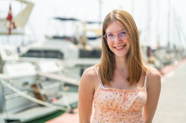 Açık havada gözlüklü genç bir Fransız kız Neşeli bir ifadeyle