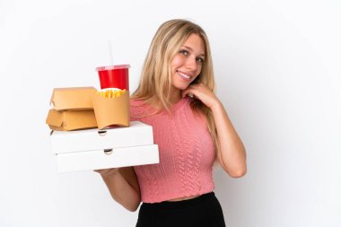 Mavi arka planda şişman yiyecekler taşıyan beyaz bir kadın kahkaha atıyor.