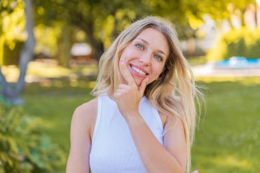 Açık havada gülümseyen genç sarışın kadın.