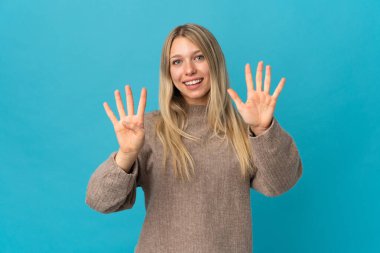 Mavi arka planda izole edilmiş genç sarışın kadın parmaklarıyla dokuzu sayıyor.