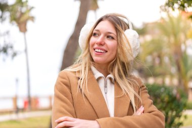 Sarışın, güzel bir kadın, açık havada kışın kuklalar takıyor, mutlu ve gülümsüyor.