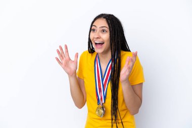 Saç örgüleri ve madalyaları olan genç bir kız izole edilmiş pembe bir arka plan ve şaşırtıcı bir yüz ifadesi var.