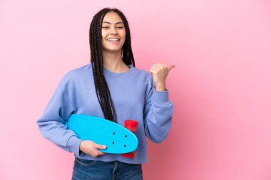 Pembe arka planda örgülü genç bir kız. Paten kayıyor ve yan tarafı işaret ediyor.