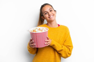 Beyaz arka planda izole edilmiş beyaz bir kadın elinde koca bir kova patlamış mısır tutuyor.