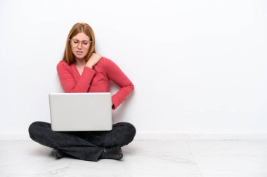 Dizüstü bilgisayarı olan genç kızıl saçlı kadın, beyaz arka planda izole bir şekilde oturuyordu. Omuz ağrısı çekiyordu.