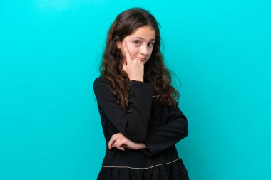 Mavi arka planda izole edilmiş küçük kız bir fikir düşünüyor.