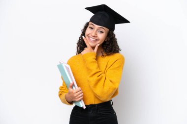 Arap üniversite mezunu kadın elinde kitaplarla beyaz arka planda mutlu ve gülümsüyor.