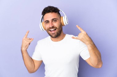 Mor arka planda izole edilmiş beyaz bir adam rock hareketleri yapan müzik dinliyor.