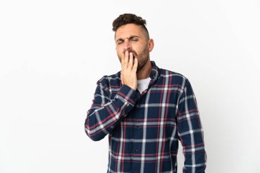 Beyaz arka planda izole edilmiş beyaz bir adam esniyor ve geniş bir ağzı eliyle kapatıyor.