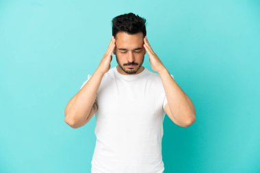Kafkasyalı genç adam mavi arka planda izole edilmiş, baş ağrısı var.
