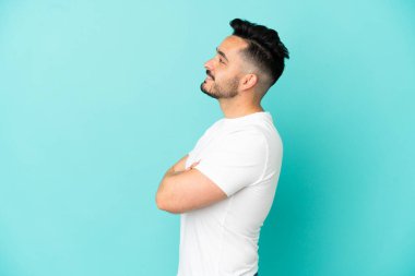 Kafkasyalı genç adam mavi arka planda yan pozisyonda izole edildi.