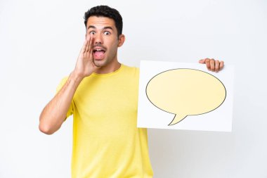 Young handsome man over isolated white background holding a placard with speech bubble icon and shouting