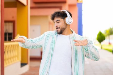 Açık havada müzik dinleyen ve dans eden yakışıklı bir Arap.