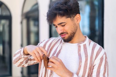 Dışarıdaki yakışıklı bir Arap 'ın elinde cüzdan ve hüzünlü bir ifadeyle