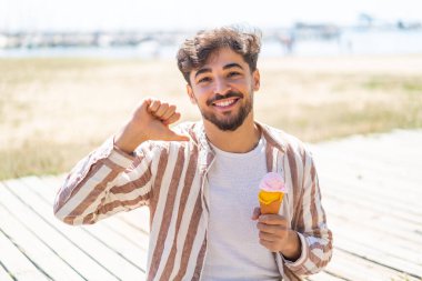 Açık havada kornet dondurması olan yakışıklı bir Arap gururlu ve kendini beğenmiş.