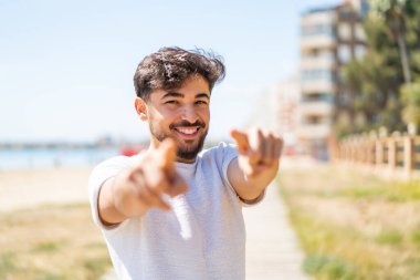 Dışarıdaki yakışıklı Arap adam gülümserken seni işaret ediyor.
